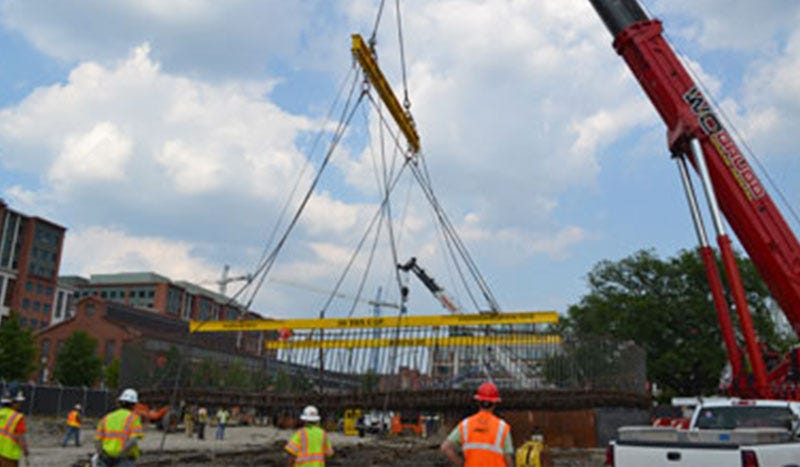 Men on jobsite overseeing lifting beam